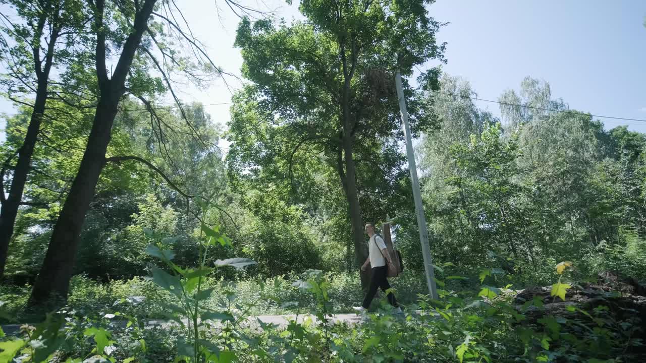 숲 근처의 거리에서 기타를 들고 는 젊은 남자