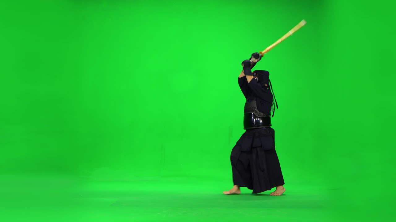 guerrero de kendo masculino practicando el arte marcial con el bokken de bambú en la pantalla verde