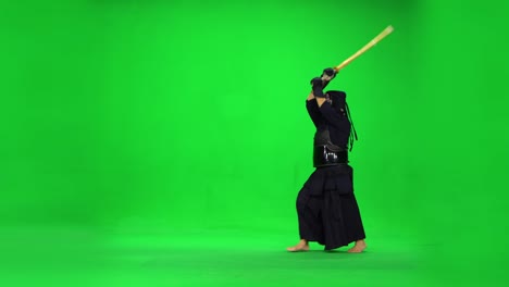 masculine kendo warrior practicing martial art with the bamboo bokken on green screen