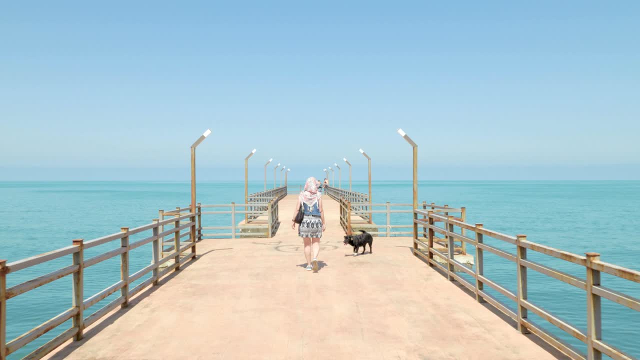 Girl walking with the funny small dog on the pier. Batumi, Georgia