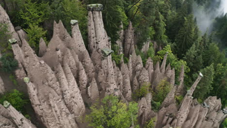 aerial view circling over the rittner erdpyramiden pillars, in misty tyrol, italy