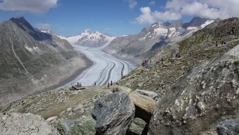 people hiking on trail with awesome panorama on aletsch glacier, switzerland