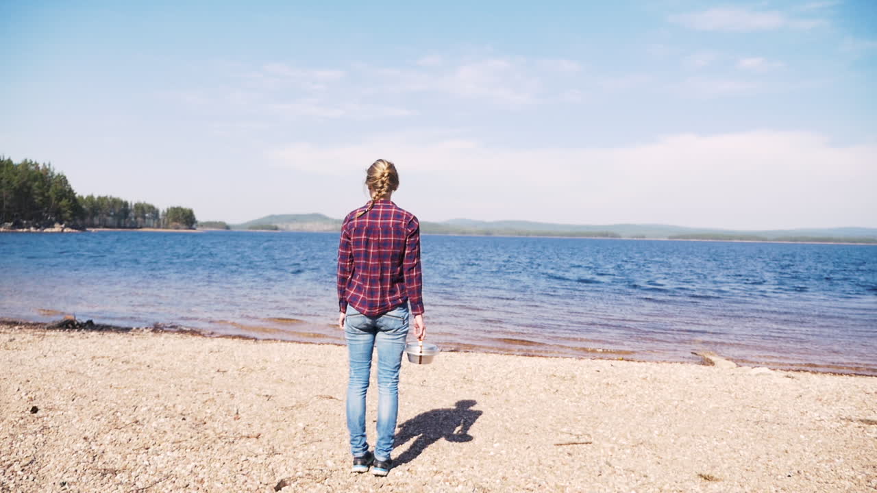 niña sueca desempacando una estufa portátil trangia en un día soleado en el lago