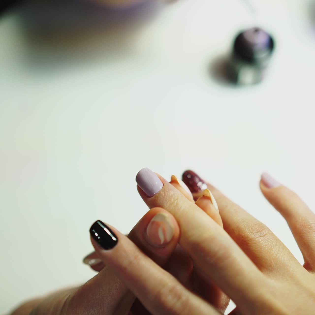 master of manicure is covering nails by gel varnish in pastel-colored on the table in the beauty salon