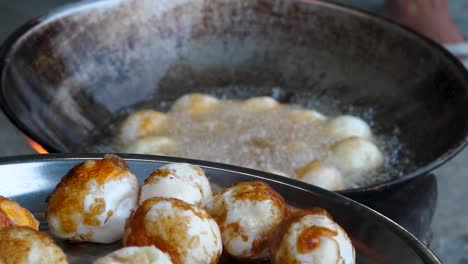 deep frying duck eggs in wok, reveal of deep fried eggs in foreground