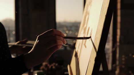 close up slow motion footage of a gifted female artist drawing with paint brush on cancas on easel.