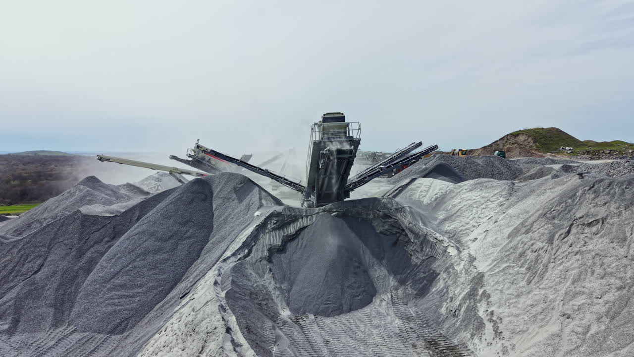 Granite quarry activity showing processing equipment and large piles of stone material in a mining environment