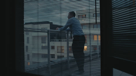 a sad man in a shirt smokes a cigarette on the balcony