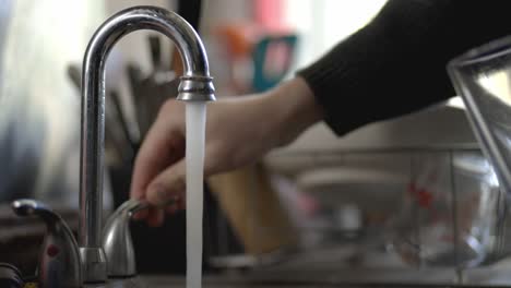 llenar un vaso de agua del grifo de la cocina de acero inoxidable