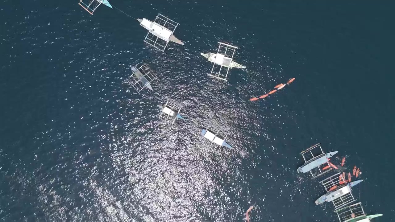 Top down drone view of bangka boats and kayaks on dark blue El Nido water