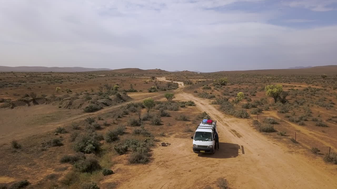 Avustralya taşrası tepelerini ortaya çıkarmak için beyaz karavanın etrafında dönen drone