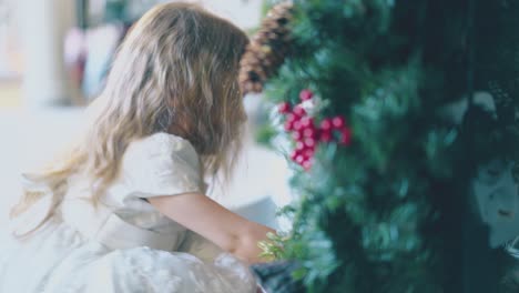 girl in holiday dress looks at christmas garland in room