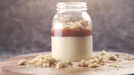 layered strawberry panna cotta in a jar with crumble topping