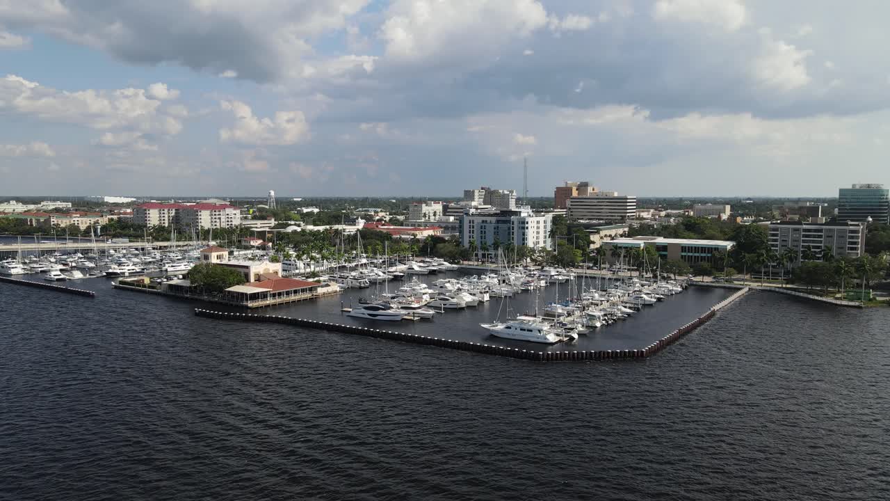Aerial view of Bradenton marina with boats docked and the city skyline over the Manatee River. Crane Down Left Day