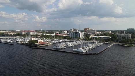 aerial view of bradenton marina with boats docked and the city skyline over the manatee river. crane down left day