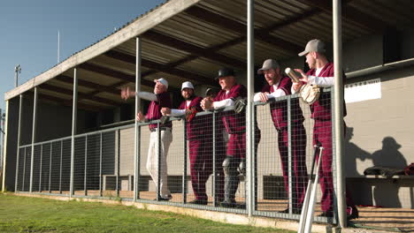 baseball players in dugout cheering and clapping during game, wearing uniforms