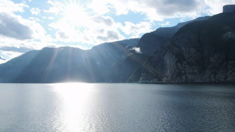 Spectral-sun-shines-on-ocean,-granite-cliffs-rise-high-from-the-water