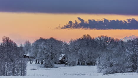 timelapse shot of sunset during evening time along snow covered ground beside village houses with clouds passing by