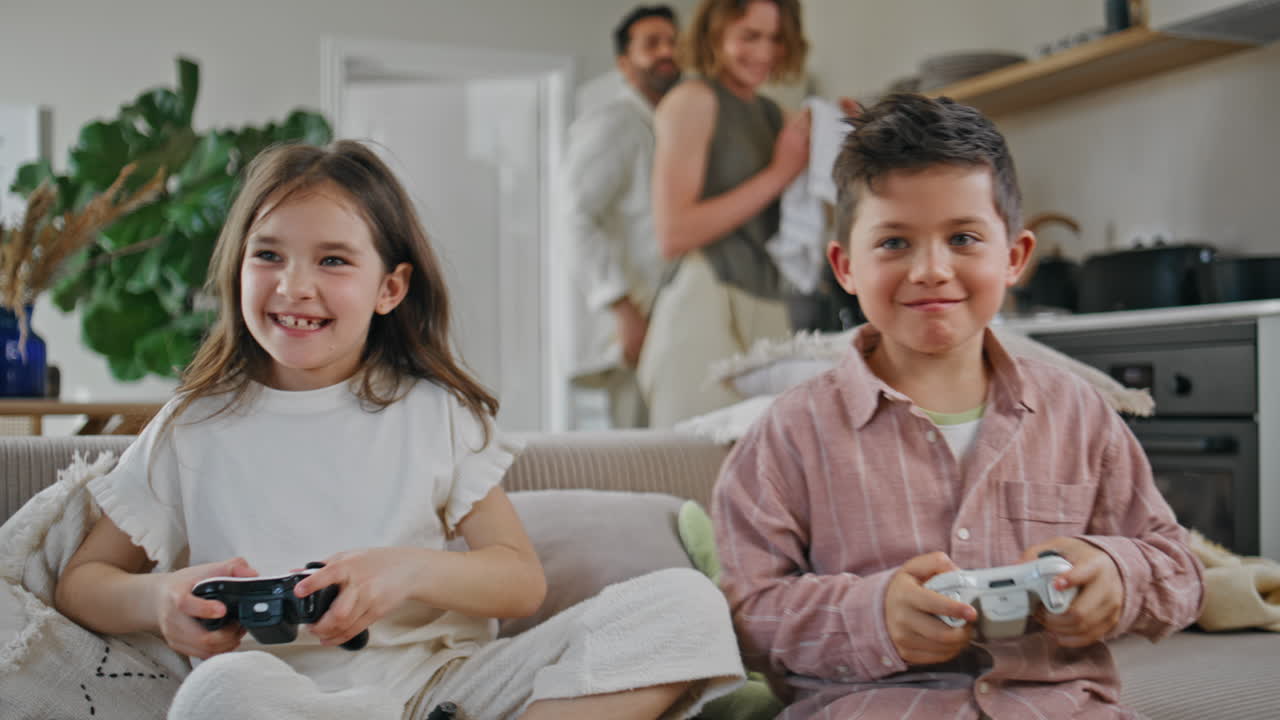 Laughing kids playing controllers at living room closeup. Funny brother sister