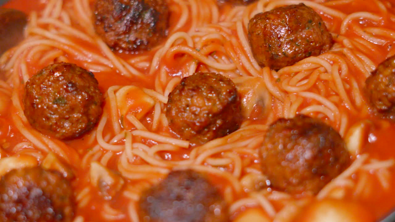 Top Down Rotating Shot of Italian Meatballs with Spaghetti Pasta in Rich Tomato Sauce Bubbling in Slow Motion. Homemade Cooking Food Footage.