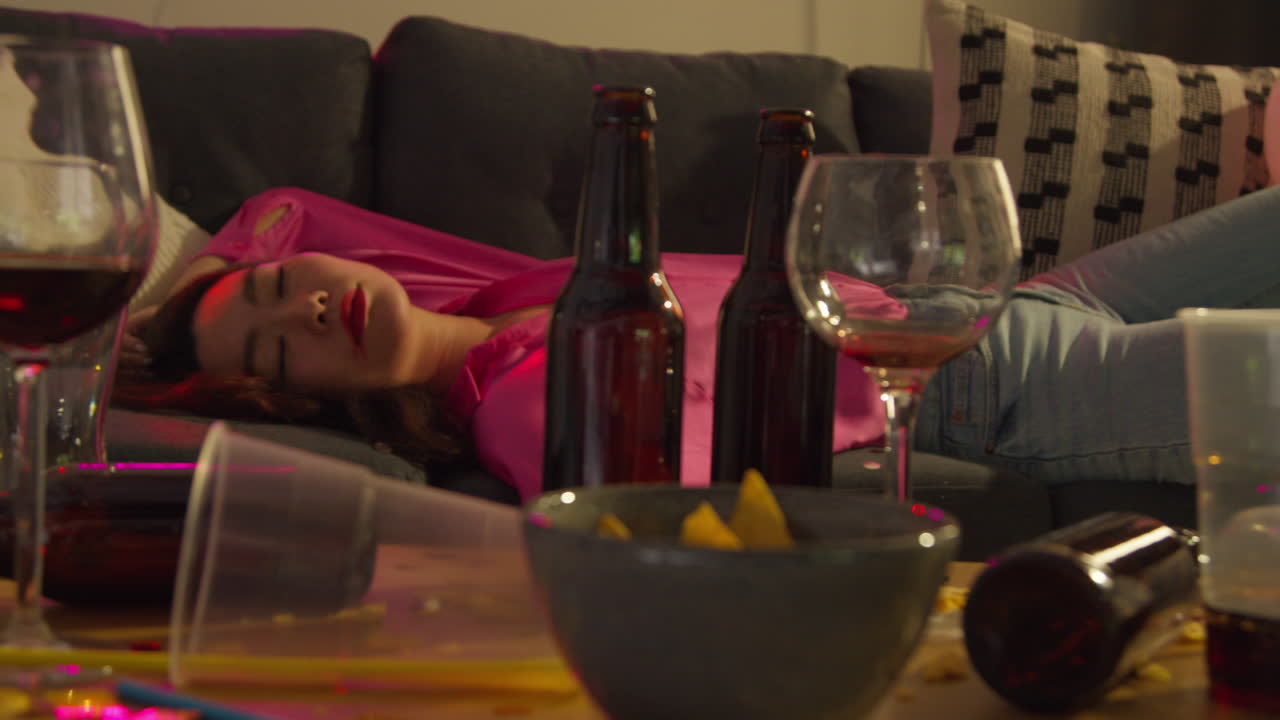 집 파티에서 술을 마신 후 소파에 쓰러진 여자가 숙취로 고통 받고 있습니다.