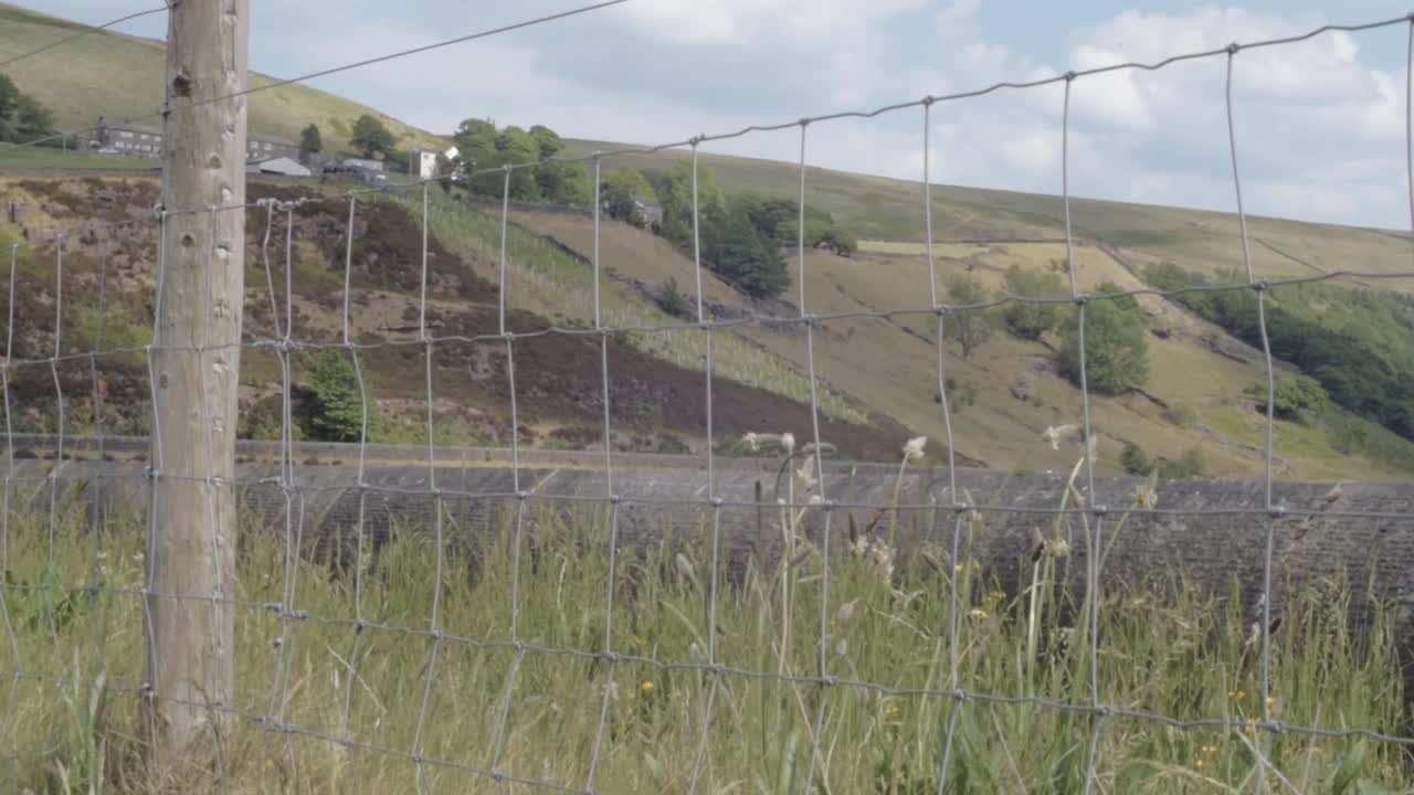 View of Yorkshire hills at Butterley reservoir wide tilting shot through fence