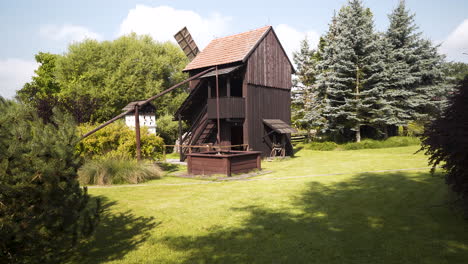 Wooden-mill-and-waterpump-in-a-garden-with-evergreens,Czechia,zooming