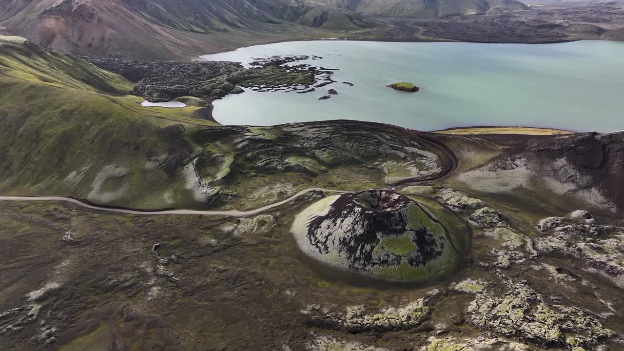 Stutur crater in Icelandic highlands during sunny day. Aerial tilt up wide shot. Blue glacial lake in background