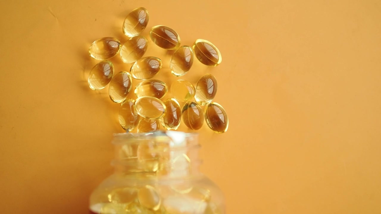 Capsule dorate di olio di pesce Omega-3 rovesciate dalla bottiglia