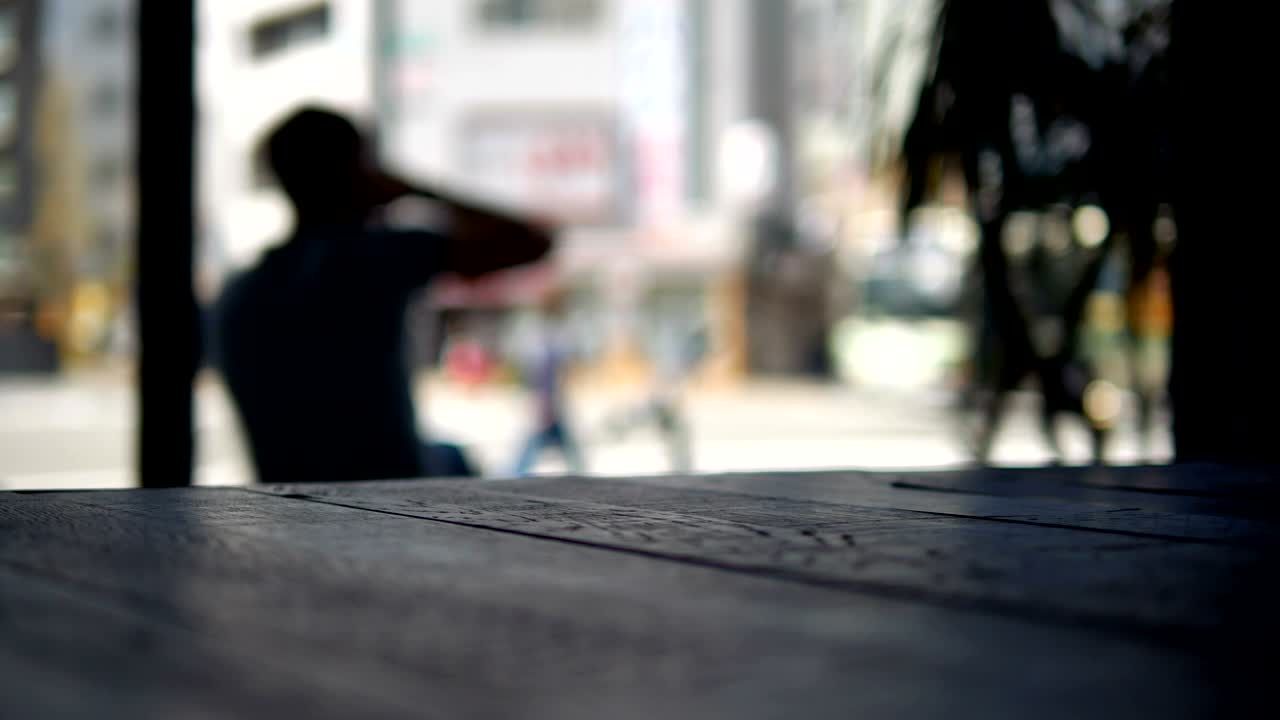 커피를 마시고 커피 앞에 앉아있는 남자의 흐릿한 배경의 영상과 전면에 있는 나무 테이블