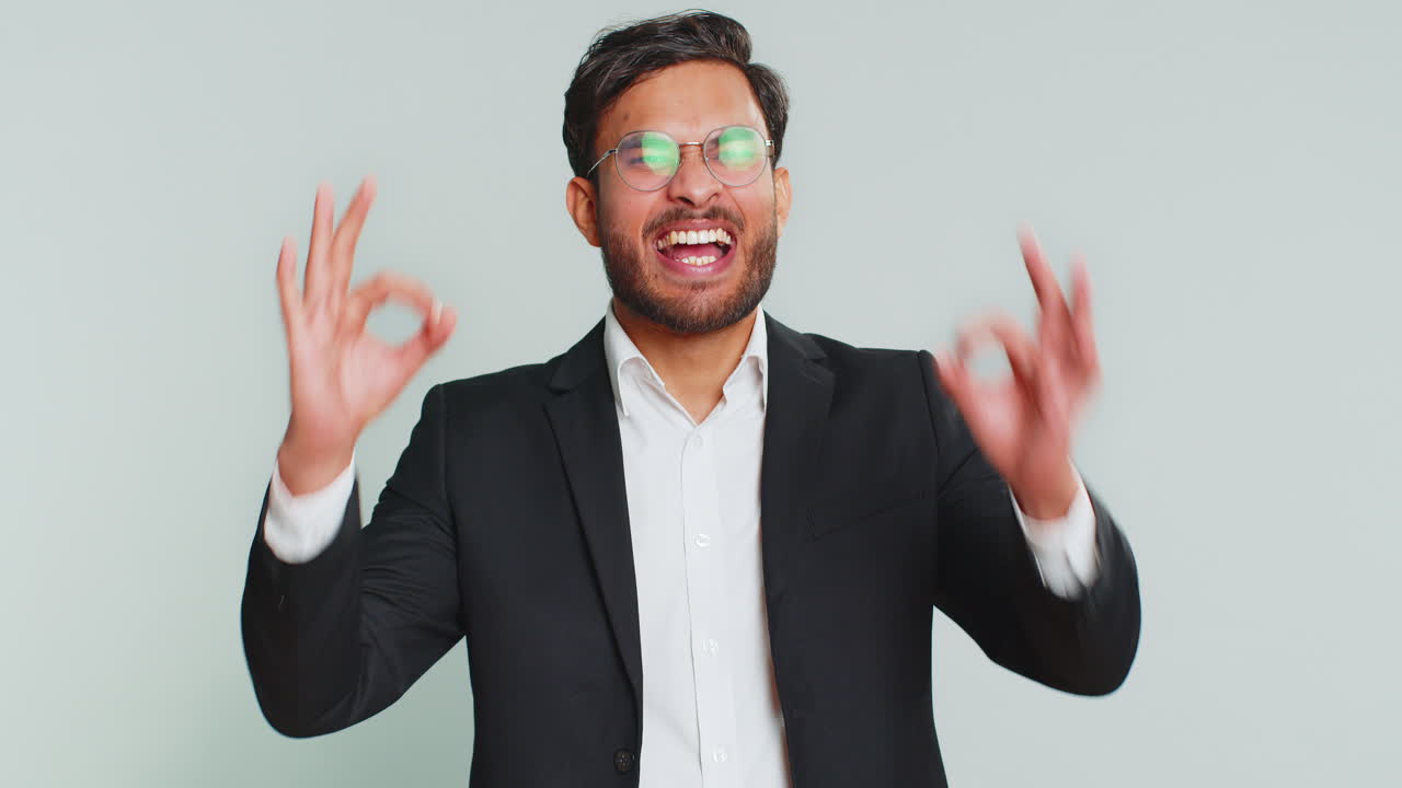 Empresário feliz fazendo o sinal de 'ok', que representa feedback positivo, celebração de vitória e aprovação de ideias.