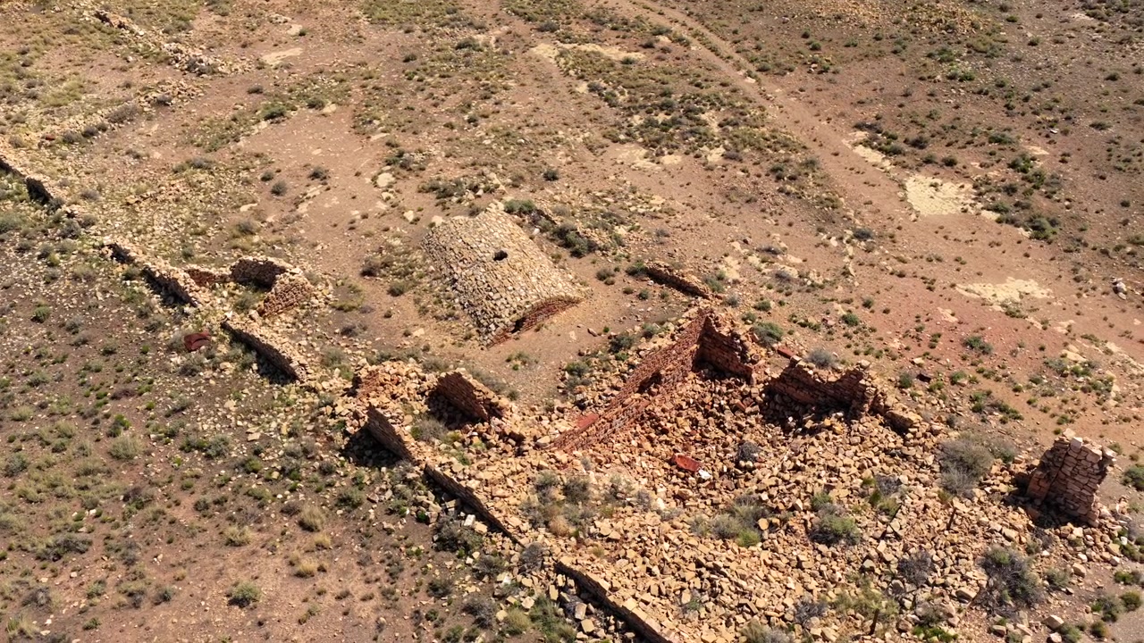 Vol de drone 4K UHD au-dessus de ruines étranges et hantées se dressant seules dans le vaste désert de l'Arizona. Ces mystérieux vestiges de pionniers présentent des murs effondrés et des débris éparpillés d'un passé oublié.