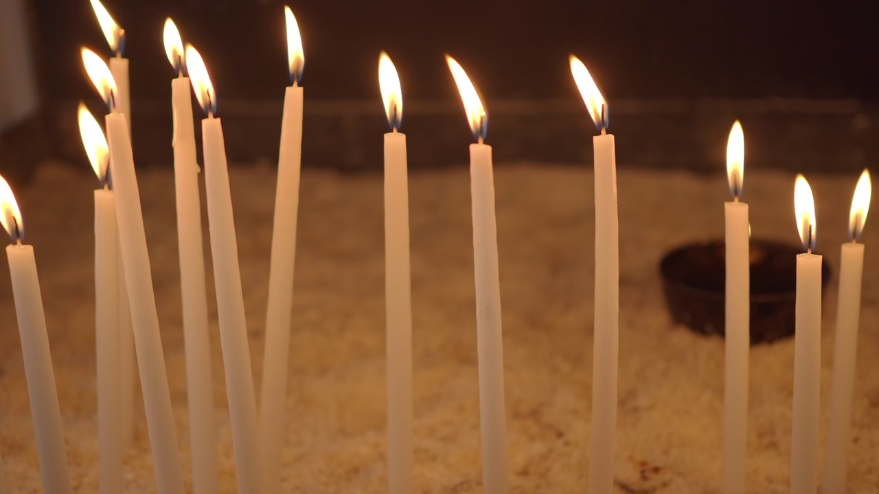 Fiamme tremolanti di candele bianche in un ambiente spirituale