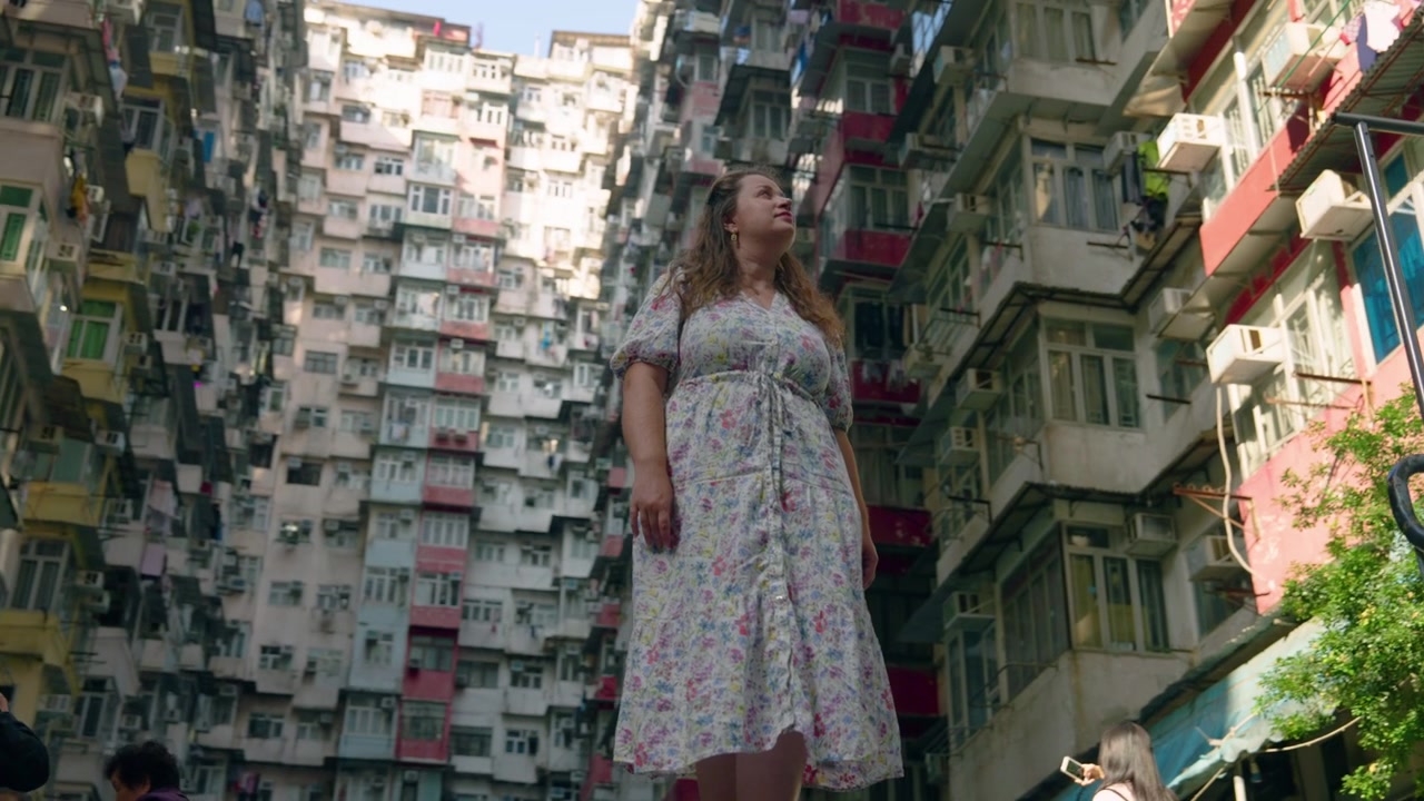 Viaggiatrice che osserva il complesso residenziale a molti piani del Monster Building a Hong Kong, Cina. Ripresa rotante a bassa angolazione.