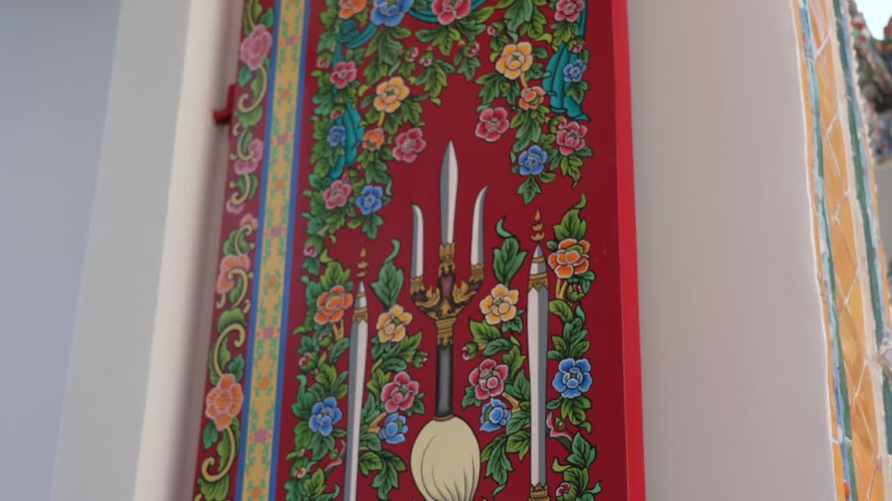 Colorful floral mural on a red wall at Wat Pho, Bangkok, Thailand, showcasing intricate Thai craftsmanship and temple artistry