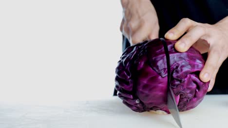 4k women hand cutting fresh red cabbage on cutting board. female hand slices raw red cabbage into little slide with knife on cutting board. healthy food concept.