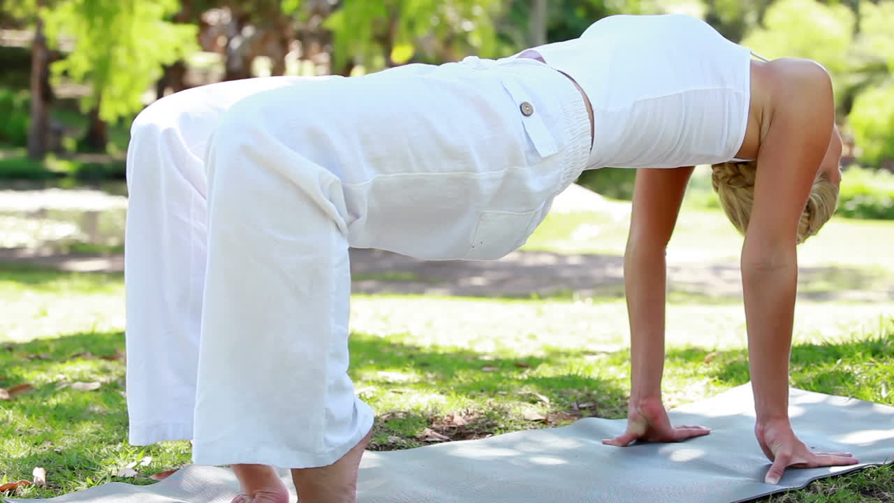 una mujer sosteniendo una posición de yoga en el parque