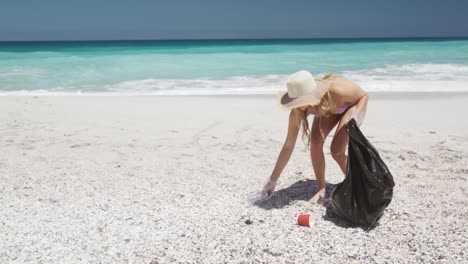 mujer recogiendo basura en la playa y poniéndola en bolsas de basura