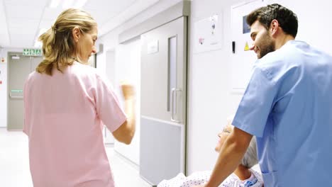 Krankenschwester-Schiebt-Einen-Patienten-Im-Rollstuhl,-Während-Sie-Mit-Einem-Arzt-Spricht