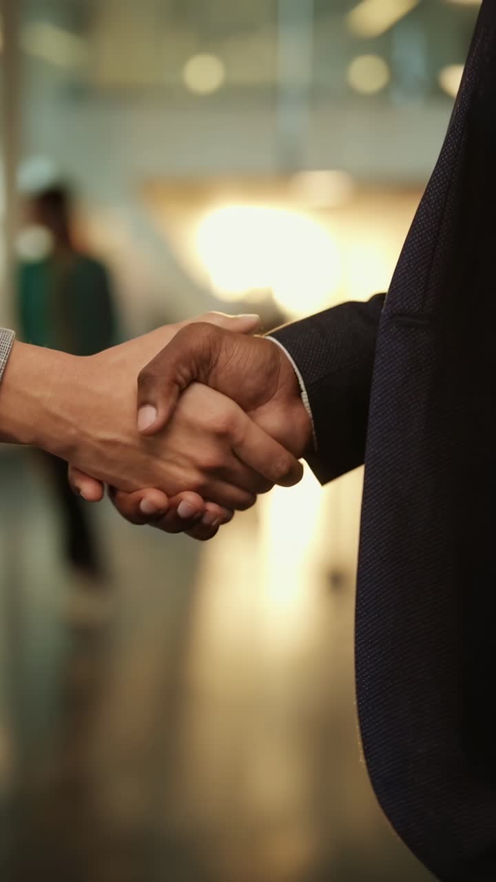 Video ravvicinato di una stretta di mano in un ufficio moderno, ripreso da un angolo laterale