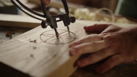 man making pattern on wooden product indoors. carpenter using tool for carving