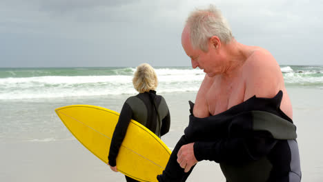 viejo hombre caucásico mayor con traje de neopreno en la playa 4k