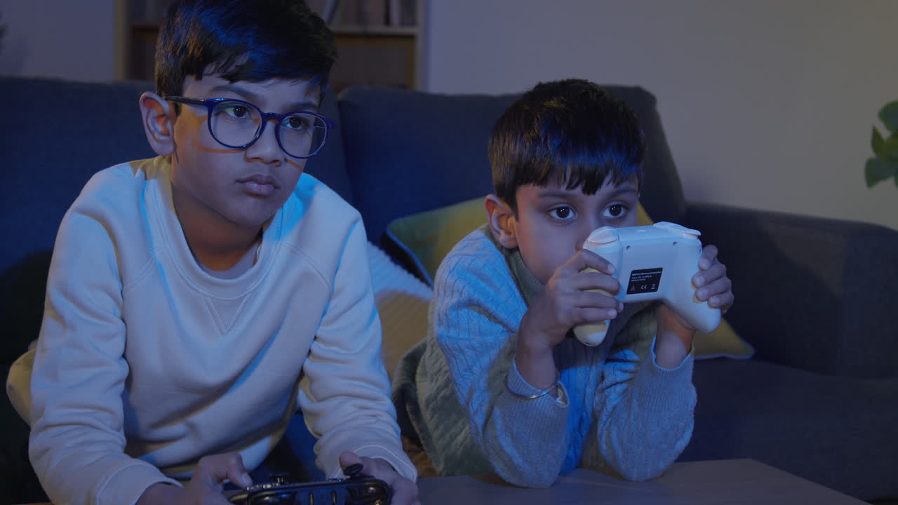 dos niños jóvenes en casa jugando con consola de juegos de computadora en la tv sosteniendo controladores tarde en la noche 5