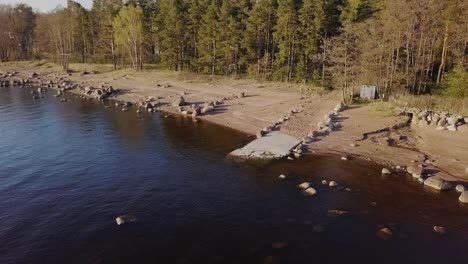 rocky beach shore with a small concrete pierce with nordic nature and deep blue water