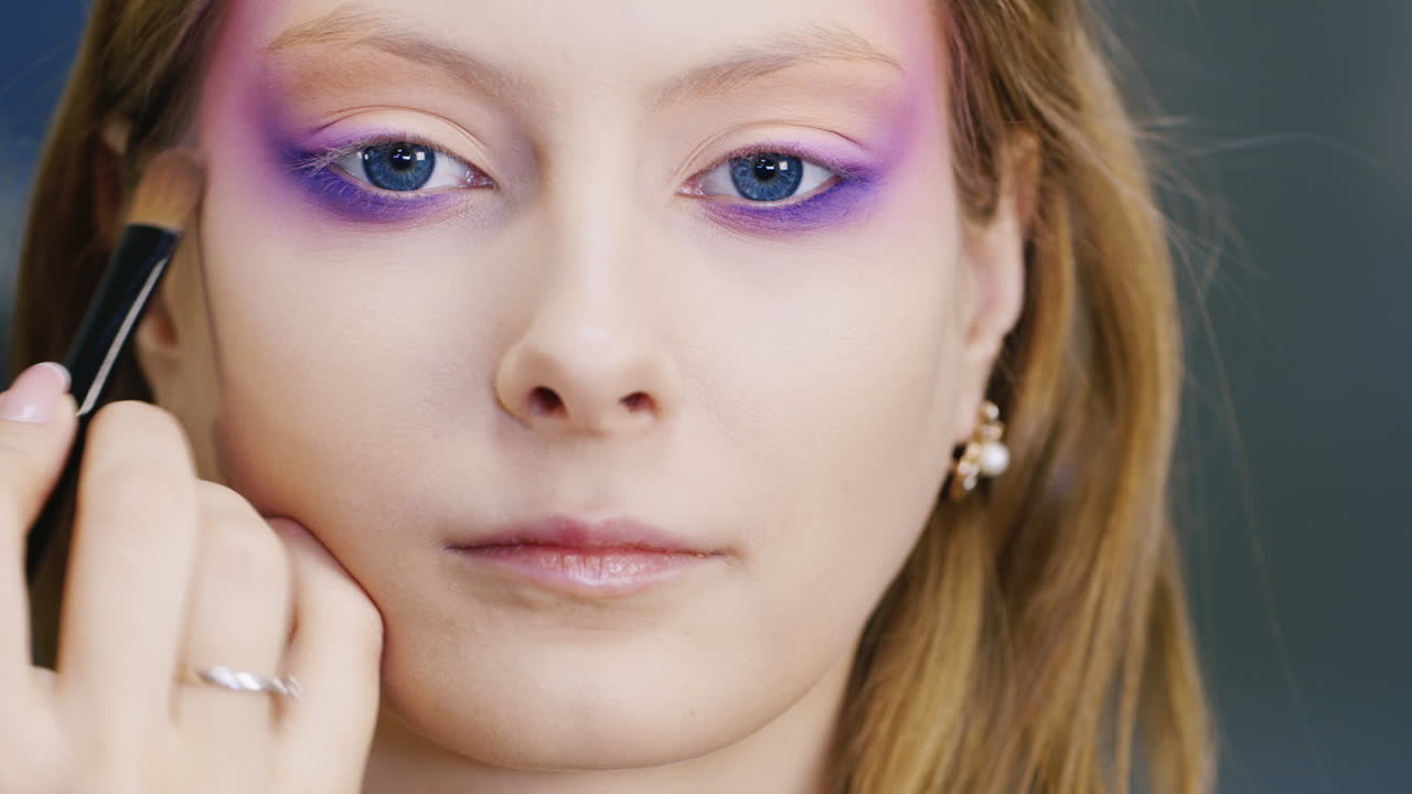 una joven mujer de ojos azules se maquilla en la cara