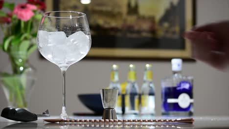 swirling ice in a large stemmed balloon glass to chill it prior to making a gin and tonic cocktail