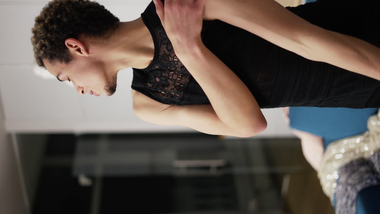 un hombre con un pequeño vestido negro se mueve sensualmente y se toca a sí mismo