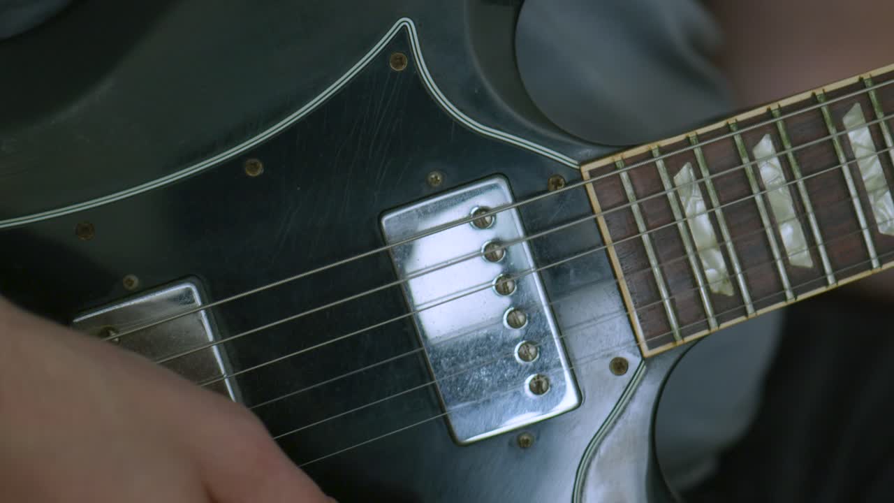 Man playing an electric guitar making rhythms with his right hand on camera