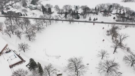 aerial, empty snow covered field in neighborhood community park during winter