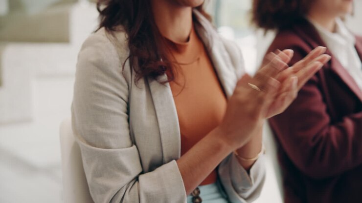 A group of women in business suits clap at a meeting